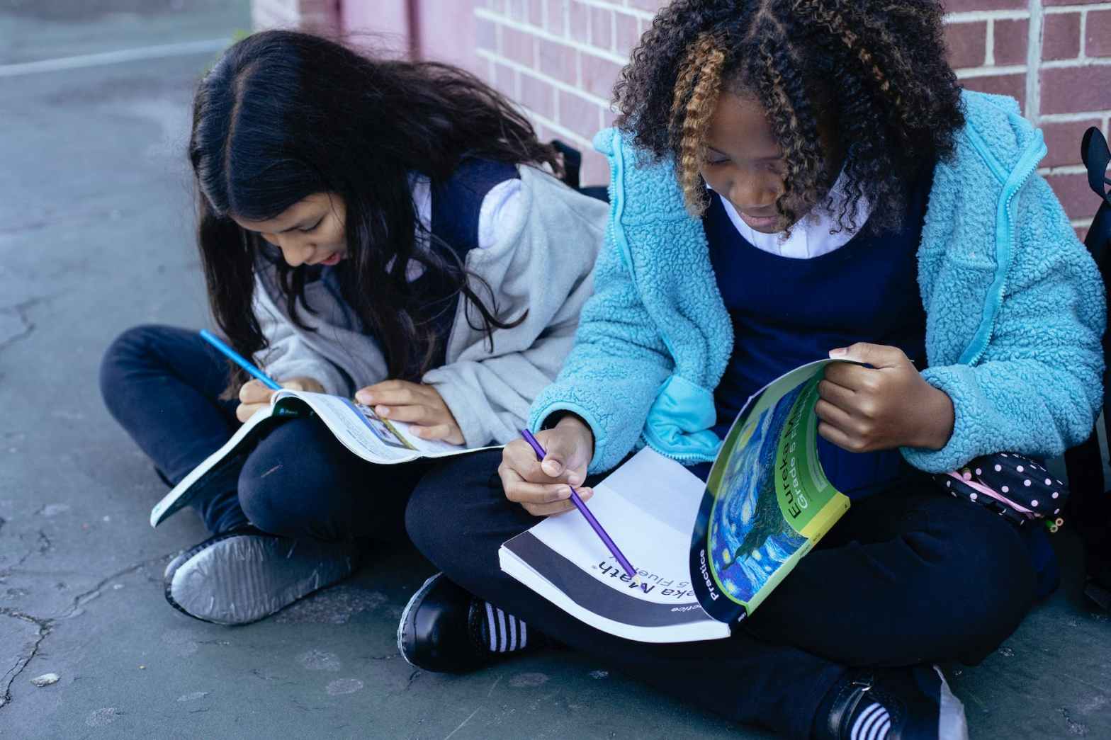 multiracial children doing exercises with pencil in textbooks